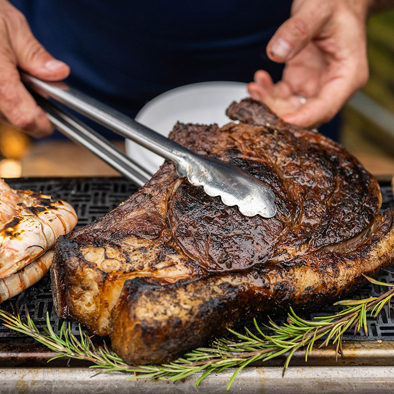 Beef rib chop cooking over fire on a Blok grill