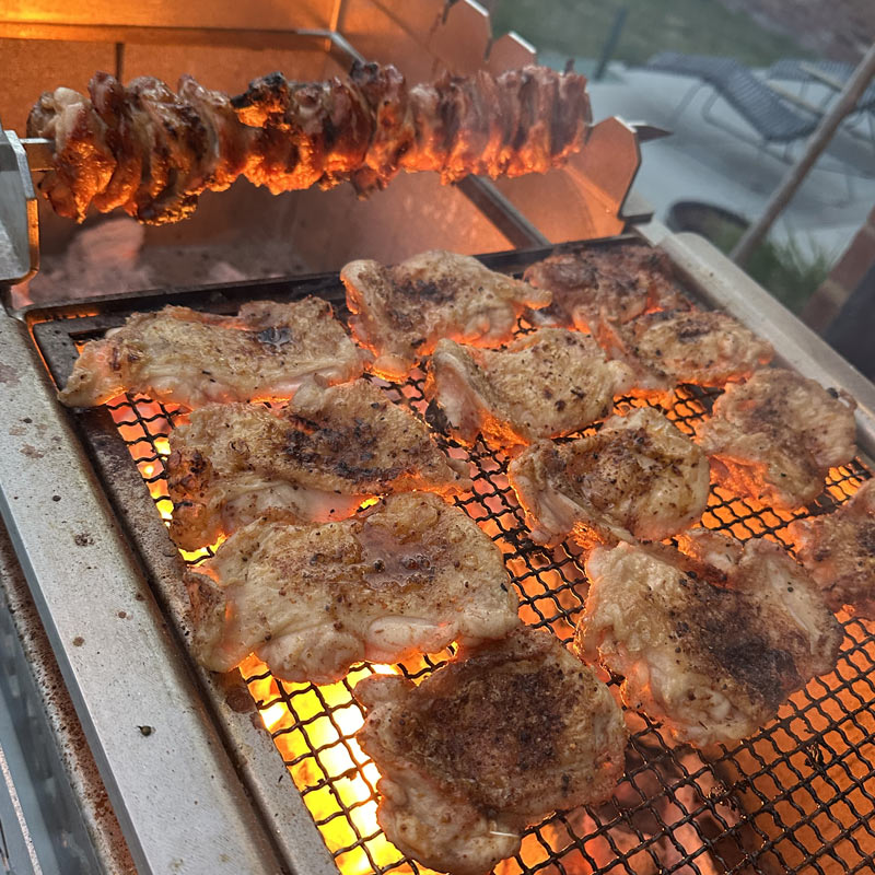 Chicken thighs and yakitori cooking over live fire