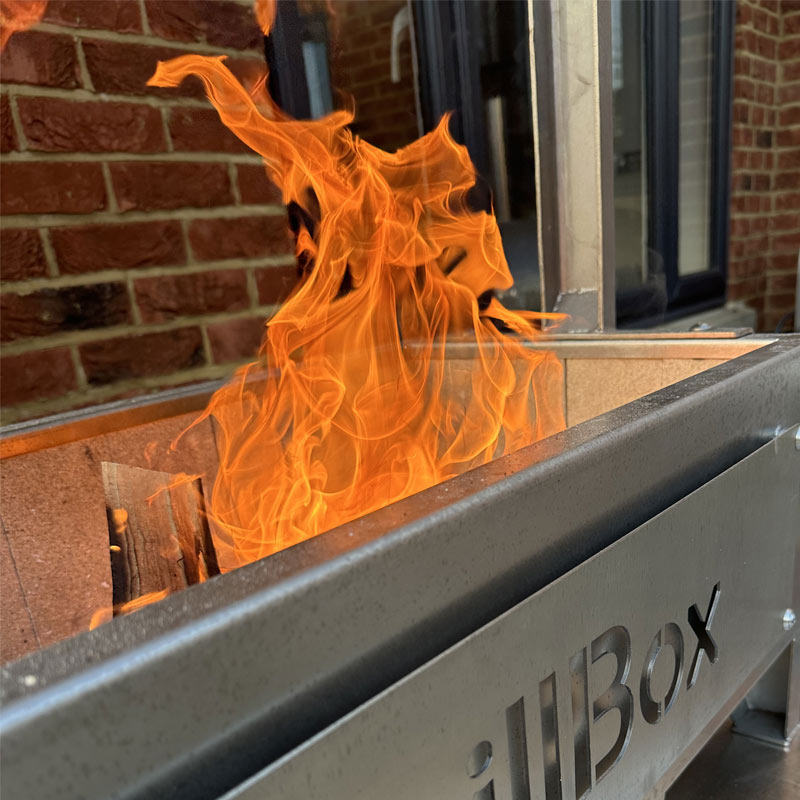 Flames rising from a live fire cooking grill