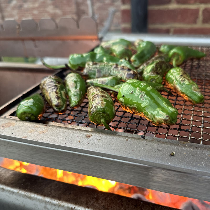 Padron peppers cooking over live fire